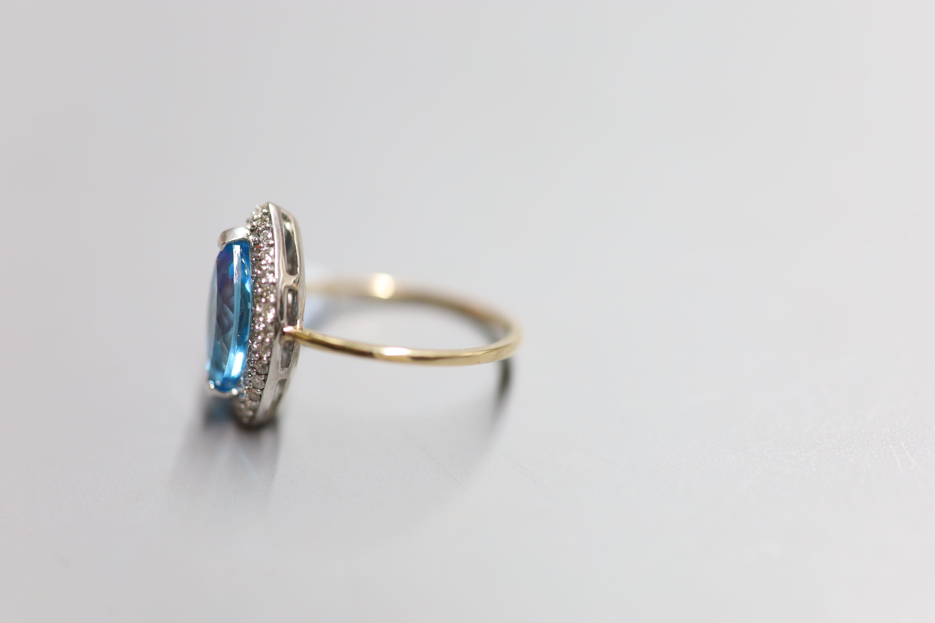 A yellow metal, blue topaz and diamond chip set marquise dress ring, size O, gross 4.2 grams.